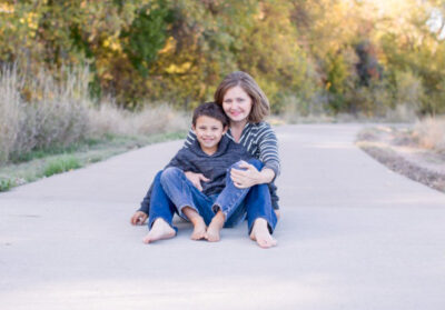 a smiling single mother and child sitting together on a sidewalk